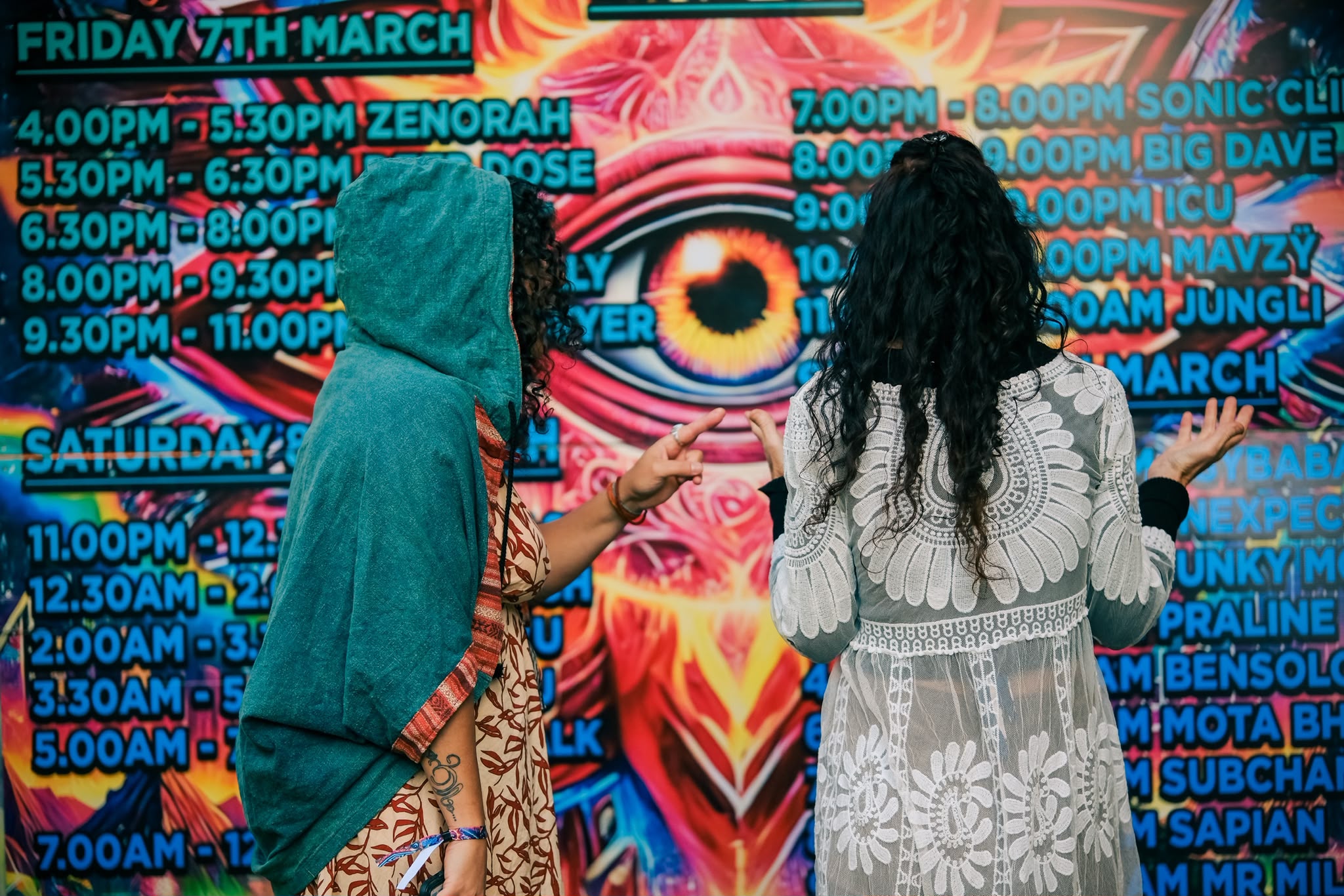 Festival guests beside a colourful previous-event timetable