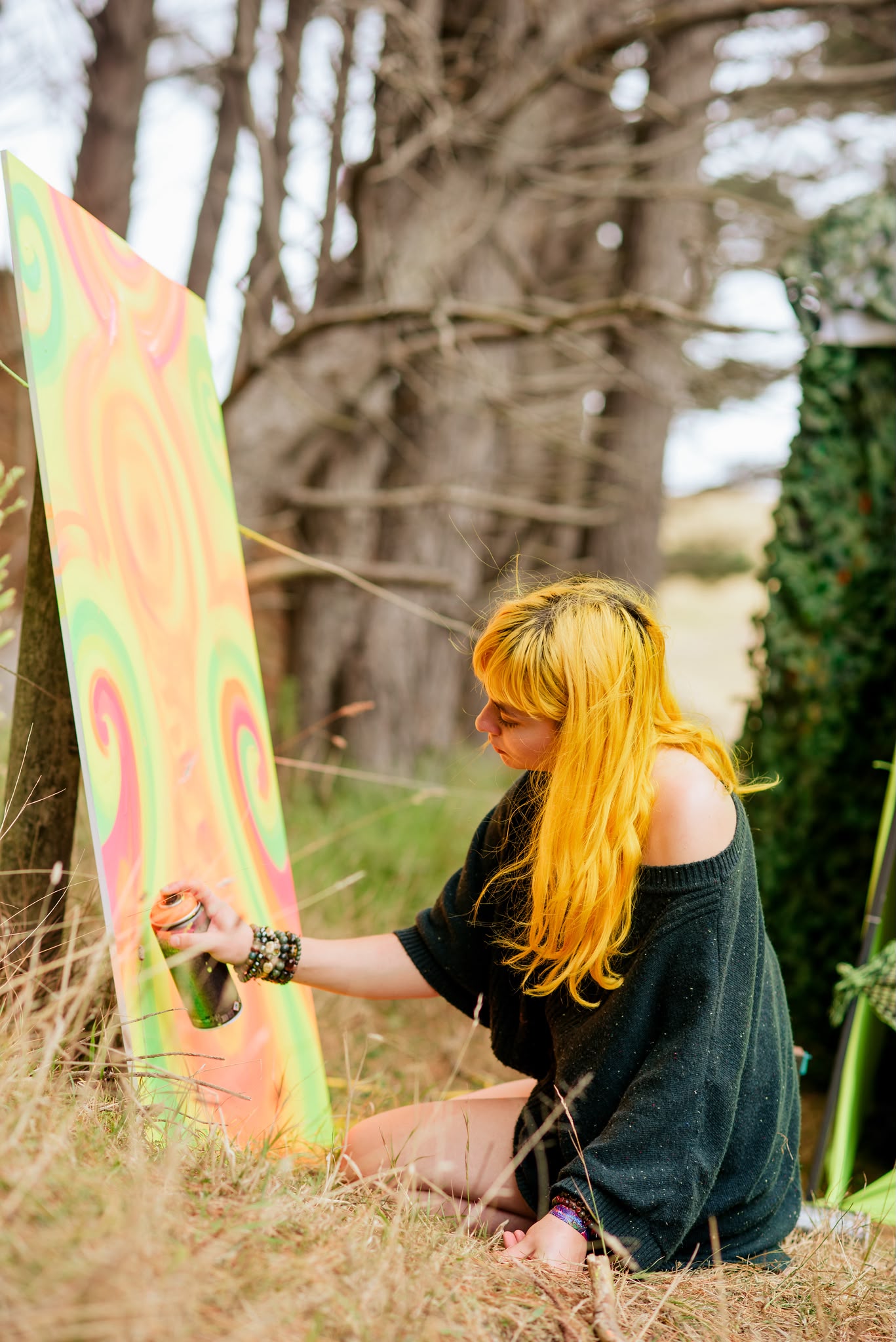 An artist spray-painting a colourful canvas outdoors