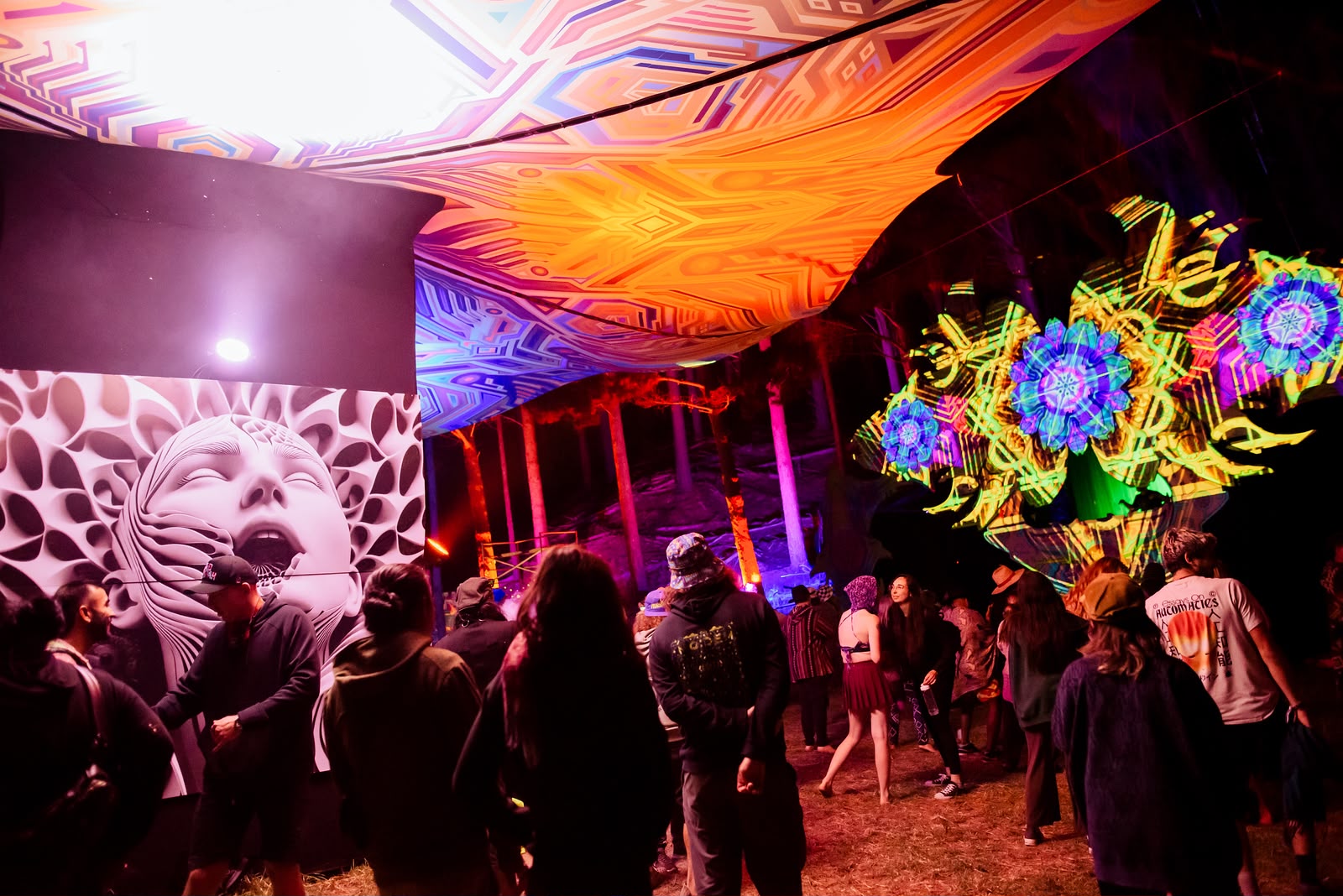 Guests beneath a glowing orange festival canopy