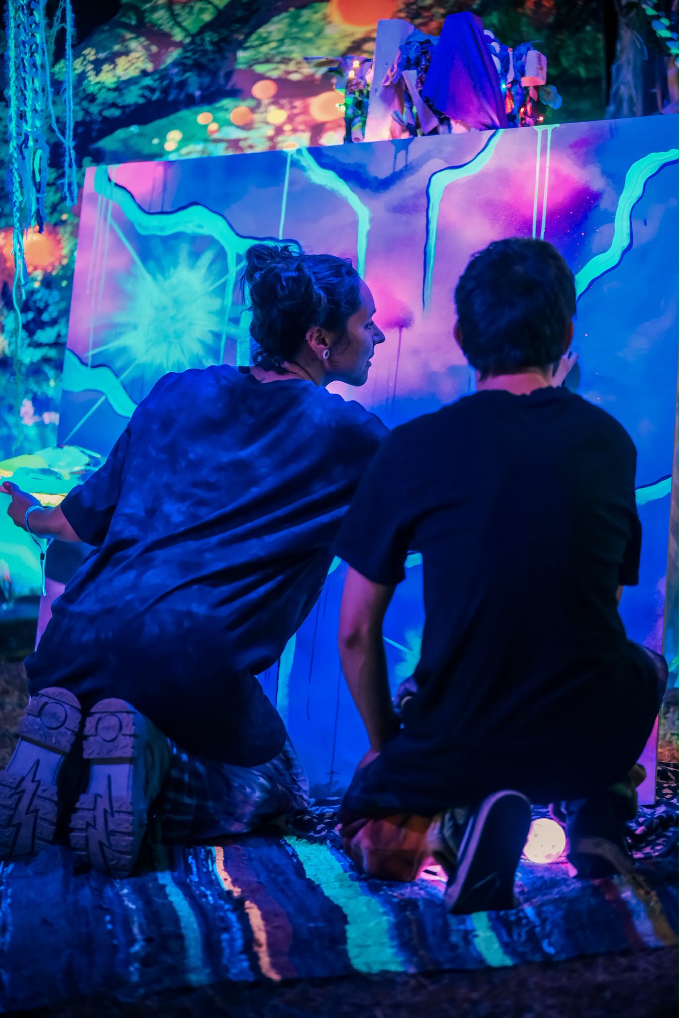Artists creating a painting under blue and violet lights
